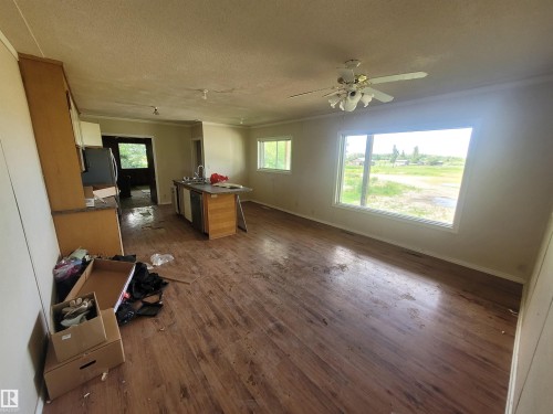 Open-concept living area with wood-finish flooring, a kitchen island with integrated sink, and an expansive window providing natural light - Rural Athabasca County, AB 