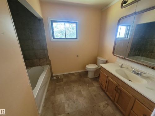 Bathroom featuring a single vanity with wood-finish cabinetry, a white countertop, and a built-in sink - Rural Athabasca County, AB 