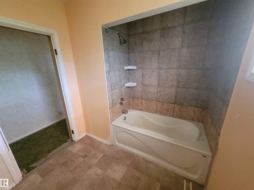 Bathroom featuring a white bathtub, ceramic tile surround, and a shower fixture - Rural Athabasca County, AB 