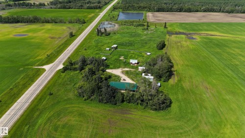Expansive agricultural property featuring a paved road frontage, multiple outbuildings, and natural ponds - Rural Athabasca County, AB 