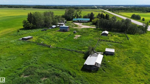 Expansive rural property featuring multiple outbuildings, mature trees, open fields, and a paved road frontage - Rural Athabasca County, AB 
