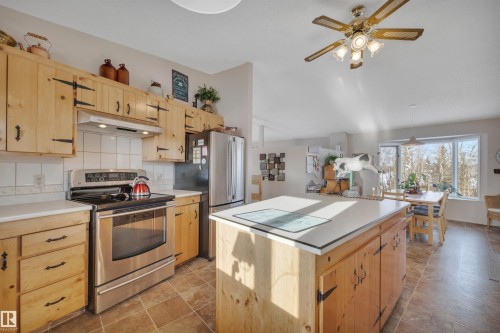 Kitchen featuring light brown cabinets, stainless steel appliances, a kitchen island, and lofted ceiling - A49375 Rr 243, Rural Leduc County, AB 