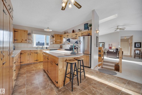 Kitchen with a ceiling fan, a kitchen breakfast bar, appliances with stainless steel finishes, open shelves, and a kitchen island - A49375 Rr 243, Rural Leduc County, AB 