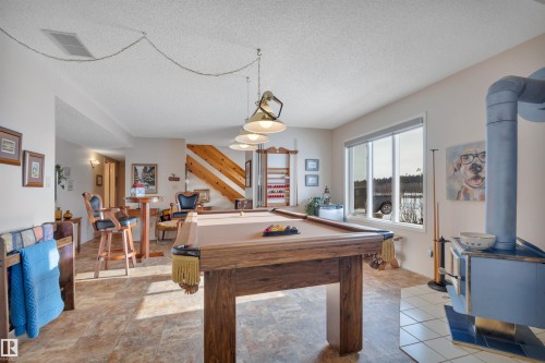 Game room featuring a wood stove, pool table, and a textured ceiling - A49375 Rr 243, Rural Leduc County, AB 