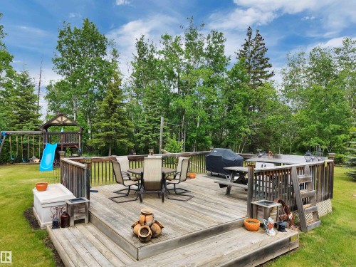 Wooden terrace featuring outdoor dining area, a grill, and view of wooded area - A49375 Rr 243, Rural Leduc County, AB 