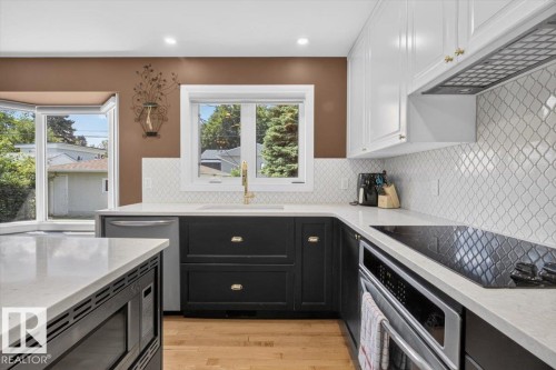 Modern kitchen featuring white shaker-style upper cabinetry and black lower cabinetry with brass hardware - 10736 48 Street, Edmonton, AB 