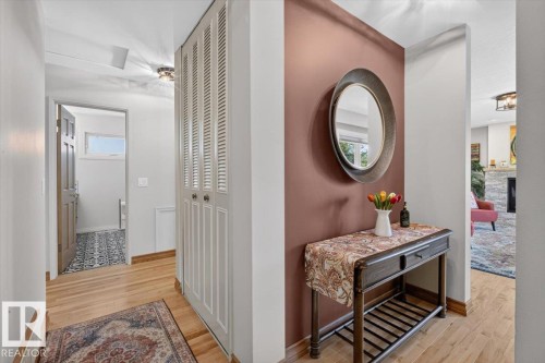 Hardwood-style flooring extends through the hallway, featuring a built-in louvered closet - 10736 48 Street, Edmonton, AB 