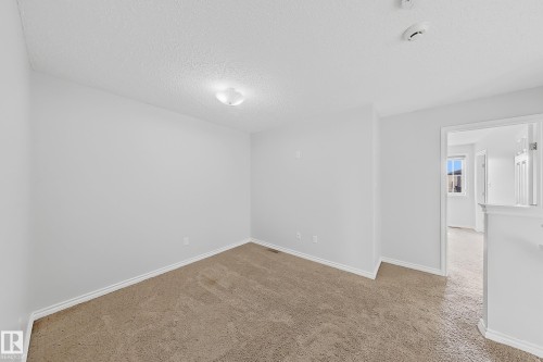 Carpeted room featuring white walls, white baseboards, and a flush-mount ceiling light fixture - 1806 28 Street Nw, Edmonton, AB 