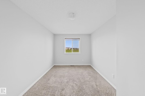 Carpeted room with a single window, white baseboards, and a flush mount ceiling light fixture - 1806 28 Street Nw, Edmonton, AB 
