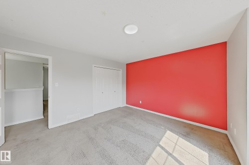 Carpeted room featuring a vibrant accent wall, neutral painted walls, white bi-fold closet doors, and recessed ceiling lighting - 1806 28 Street Nw, Edmonton, AB 