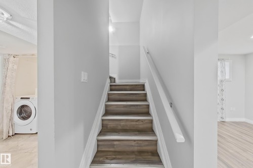 Staircase with wood-finish treads and white risers, featuring a white handrail - 1806 28 Street Nw, Edmonton, AB 