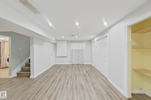 Spacious interior featuring wood-finish flooring, recessed lighting, white trim, and bi-fold closet doors - 1806 28 Street Nw, Edmonton, AB 