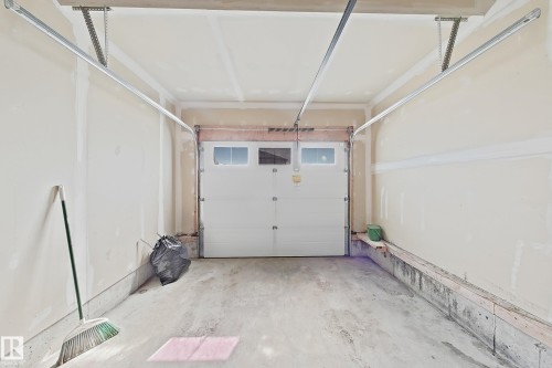 Interior garage space with a white paneled door featuring upper transom windows - 1806 28 Street Nw, Edmonton, AB 