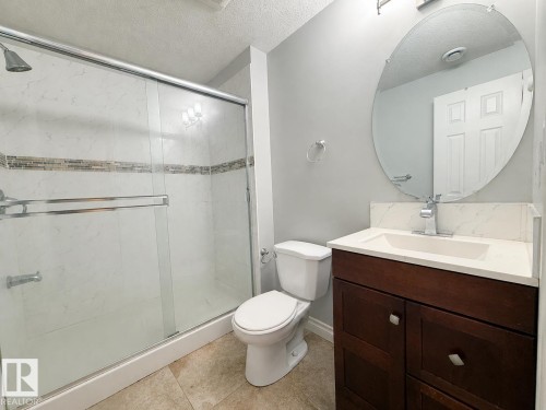 Bathroom featuring a glass-enclosed shower with tile surround and decorative mosaic accent - 1806 28 Street Nw, Edmonton, AB 