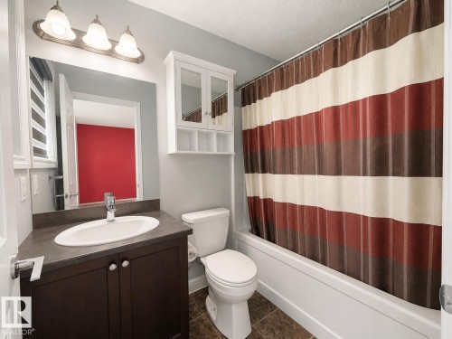 Bathroom featuring a dark wood-finish vanity with an integrated sink, a wall-mounted medicine cabinet, and a white bathtub - 1806 28 Street Nw, Edmonton, AB 