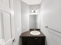 Powder room featuring a single-basin sink, dark wood-finish vanity, and wall-mounted mirror - 