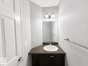 Powder room featuring a single-basin sink, dark wood-finish vanity, and wall-mounted mirror - 1806 28 Street Nw, Edmonton, AB 