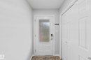 Entryway featuring a white door with frosted glass panel and smart lock, complemented by light gray walls and brown tiled flooring - 1806 28 Street Nw, Edmonton, AB 