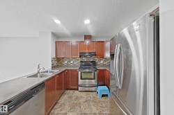 Kitchen featuring stainless steel appliances, wood cabinetry, a mosaic tile backsplash, and durable countertop surfaces - 