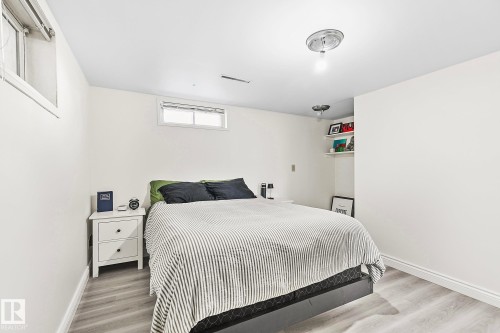 Bedroom featuring light wood-finish flooring, white painted walls, and two visible egress windows - 17059 98 Street, Edmonton, AB - Indoor Photo Showing Bedroom