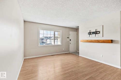 Spacious room featuring wood-finish flooring, light-toned walls, and a large multi-pane window - 17059 98 Street, Edmonton, AB - Indoor Photo Showing Other Room