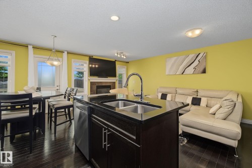 Kitchen island with a double basin sink, gooseneck faucet, and integrated dishwasher - 5205 168 Avenue, Edmonton, AB 
