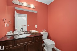 Bathroom featuring a dark wood-finish vanity with an integrated sink, a dark countertop, and a large wall mirror - 