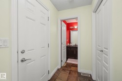 Hallway featuring a paneled door with brushed nickel hardware, light-toned walls, and a tiled floor - 