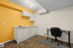 Utility area featuring a sink with a stainless steel faucet, white cabinetry, light-toned countertops, and textured tile flooring - 