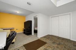 Versatile recreation area featuring a mixed flooring of carpet and multi-toned tile, a bright accent wall, and bi-fold closet doors - 
