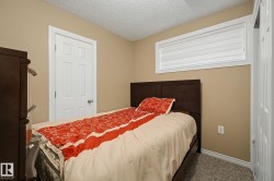 Bedroom featuring neutral-toned walls, white trim, and textured carpeting - 