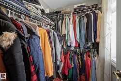 Walk-in closet featuring wire shelving, multiple hanging rods, and an interior window with sheer curtains - 