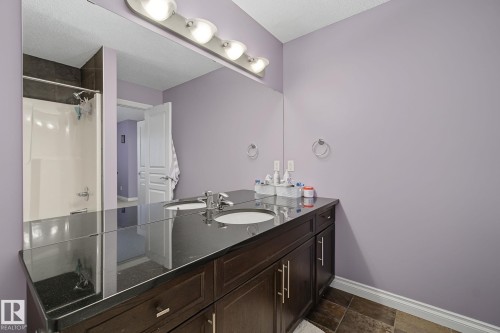 Double vanity with a dark wood-finish cabinet and a polished black countertop - 5205 168 Avenue, Edmonton, AB 