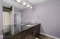 Double vanity with a dark wood-finish cabinet and a polished black countertop - 