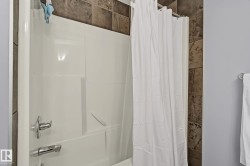 Bathtub-shower combination with a white acrylic surround, chrome fixtures, and a shower curtain rod - 