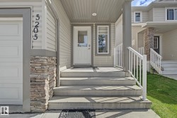 Concrete entry steps leading to a white door with an integrated window, flanked by a vertical window - 