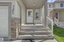 Concrete entry steps leading to a white door with an integrated window, flanked by a vertical window - 5205 168 Avenue, Edmonton, AB 
