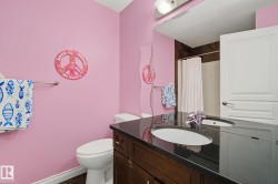 Bathroom featuring a dark wood-finish vanity, integrated sink, and dark countertop - 