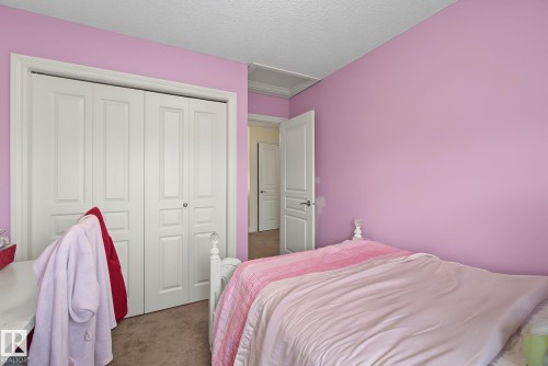 Carpeted room featuring a double bifold closet with panel doors, textured ceiling, and a white interior door - 5205 168 Avenue, Edmonton, AB 