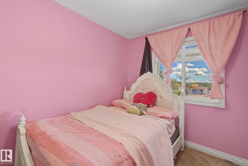 Room featuring a window with white trim, light pink walls, and a textured ceiling - 5205 168 Avenue, Edmonton, AB 