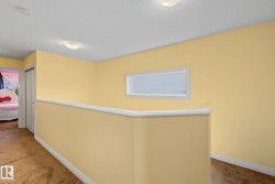 Interior hallway featuring warm yellow walls, white trim, and a white framed horizontal window - 
