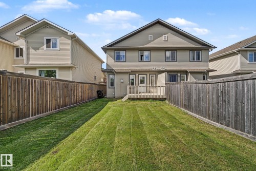 Private backyard featuring a wooden deck, expansive lawn, and full privacy fencing - 5205 168 Avenue, Edmonton, AB 