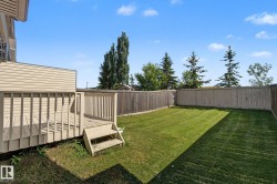 Expansive backyard featuring a wood deck with railings and steps, a large lawn area, and a perimeter wood fence - 