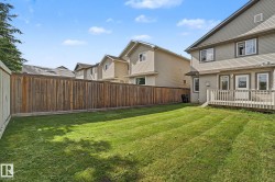 Expansive backyard featuring a manicured lawn, full privacy fencing, and a wooden deck - 
