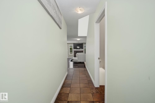 Entryway featuring square brown floor tiles, light green wall paint, white baseboards, and a semi-flush mount ceiling light - 5205 168 Avenue, Edmonton, AB 