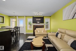 Open-concept living area featuring rich dark wood-finish flooring, a built-in fireplace with a stone surround, and an integrated media wall - 
