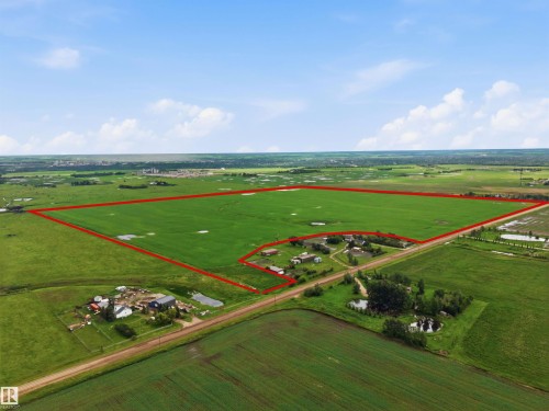 Expansive land parcel featuring substantial green acreage, visible property boundaries, multiple structures, and surrounding open fields - 55111 Range Road 230, Rural Sturgeon County, AB 