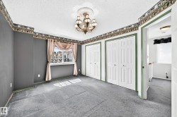 Spacious room featuring two bi-fold closet doors, a detailed ceiling medallion with a chandelier, and a large window with exterior views - 