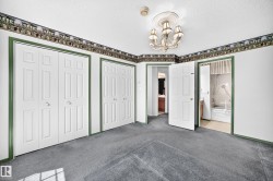 Room featuring gray carpeting, multiple bi-fold closet doors, and a decorative chandelier - 