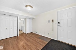 Entry area featuring wood-finish flooring, a white paneled entry door with modern hardware, and two white bi-fold closet doors - 